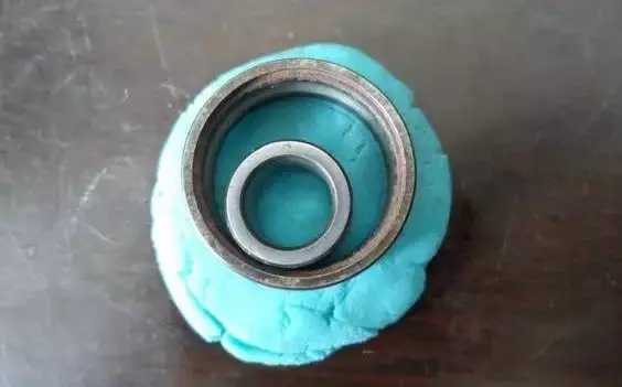 將深溝球軸承的內(nèi)外圈放到橡膠泥上,輕輕地按進去一點